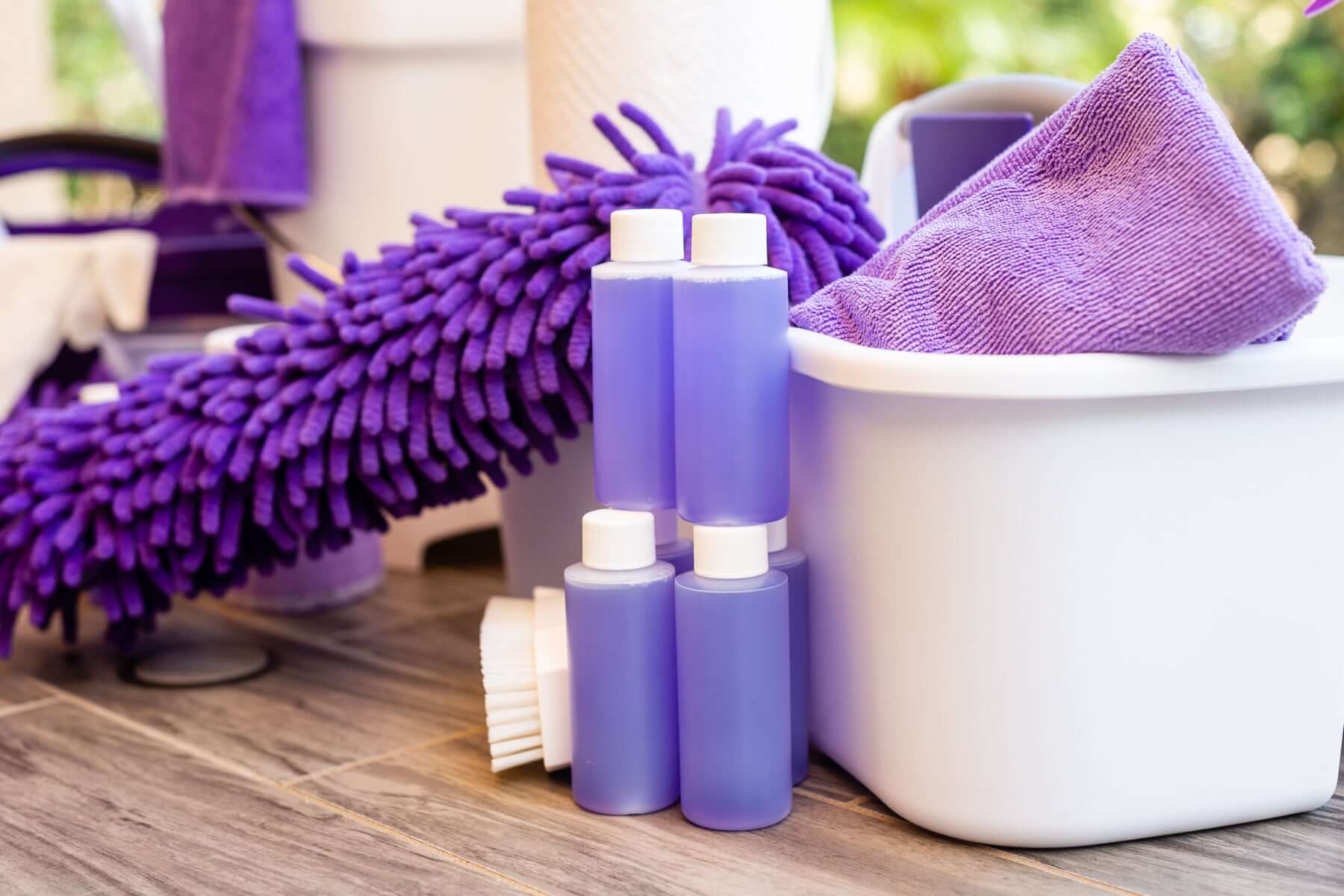Cleaning supplies in purple for house cleaning services in Venice, featuring bottles, mop, and cloths.